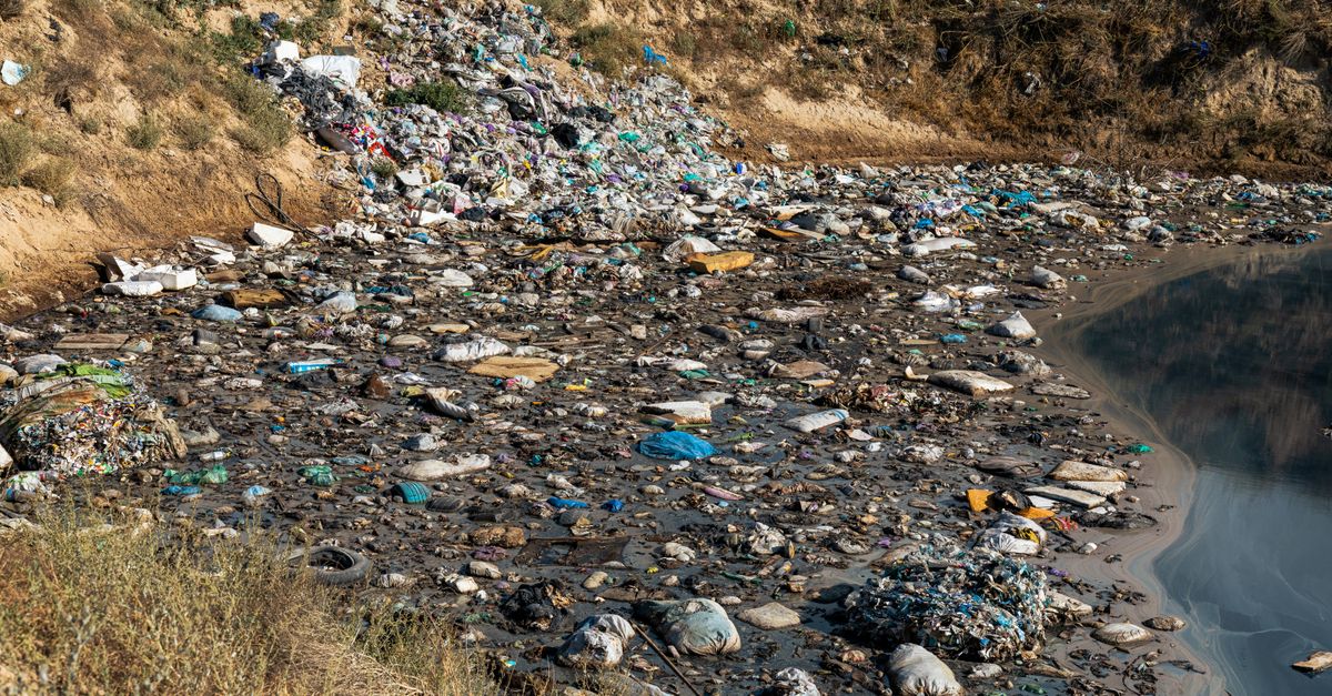 Plastic waste and debris polluting a riverbank, highlighting environmental challenges.